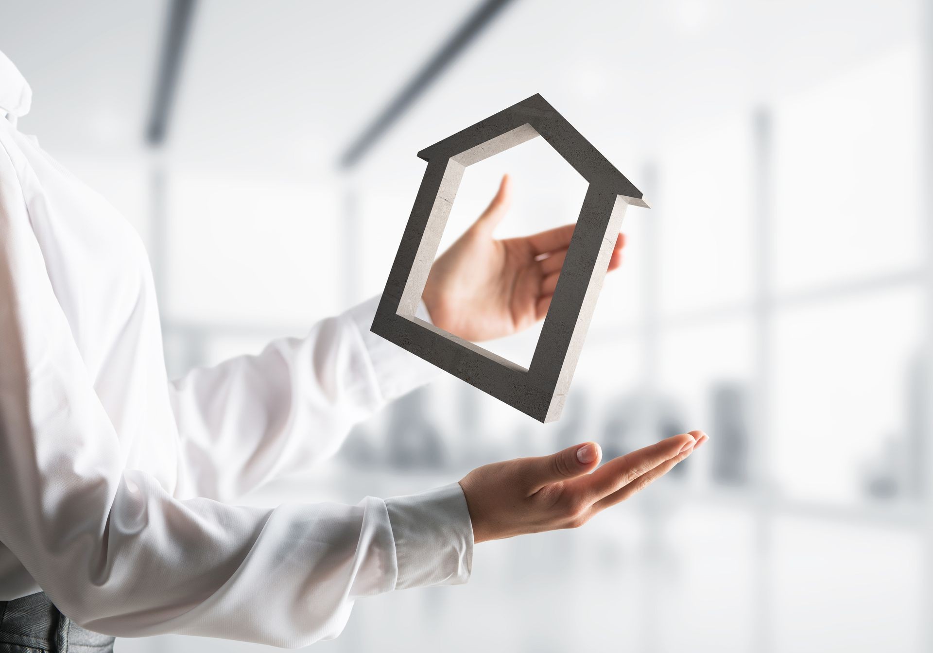 Business woman in white shirt keeping stone house symbol in hands with office view on background. Mixed media.